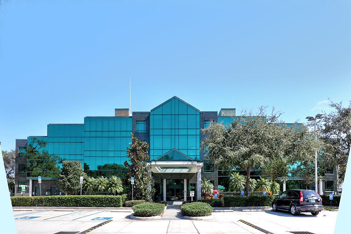 A large office building with a parking lot in front of it.