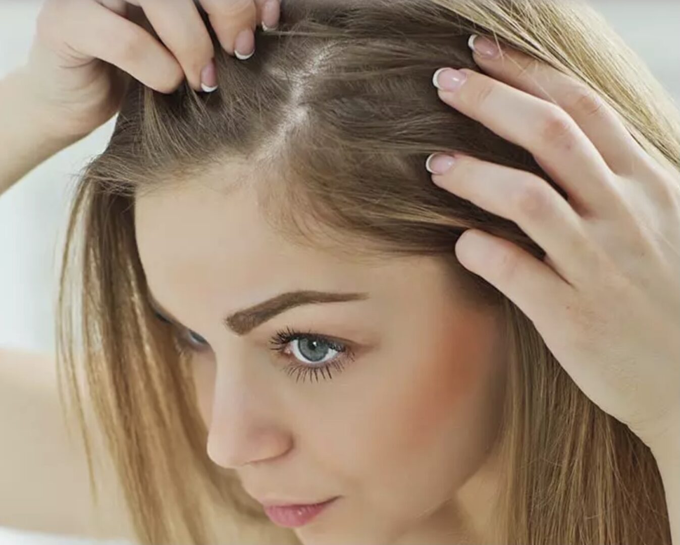 A woman is combing her hair in front of a mirror.